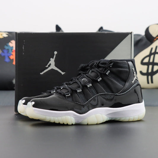 Air Jordan 11  Retro Jubilee 25th Anniversary. Black high-top sneaker with white soles in front of a Jordan box on a gray surface.