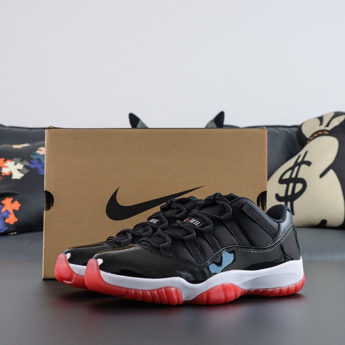 Air Jordan 11  Retro Low Bred. Black and red sneaker with a Nike box in the background
