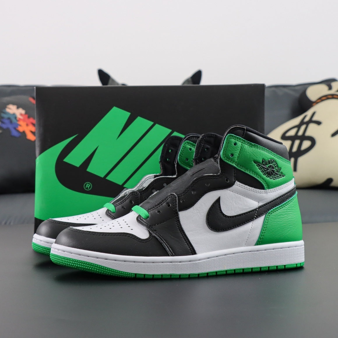 Green, black, and white sneakers with a Nike box in the background. Air Jordan 1 Retro OG High Lucky Green